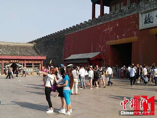 游客在故宫北门外用自拍杆合影。中新网记者 宋宇晟 摄