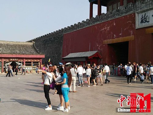 游客在故宫北门外用自拍杆合影。中新网记者 宋宇晟 摄